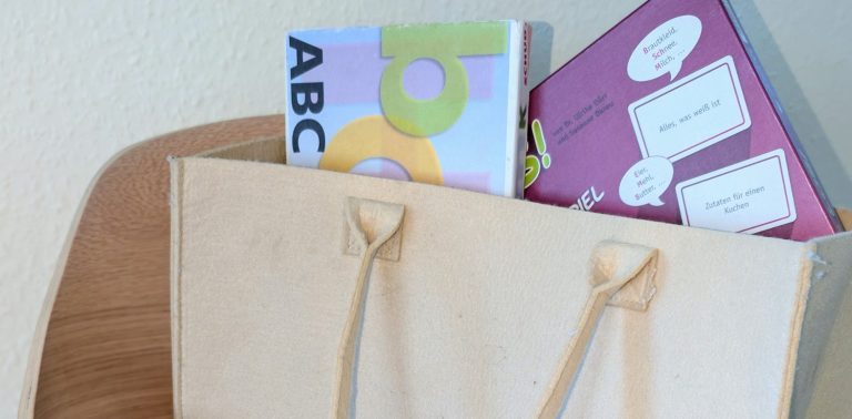 Erfolg in der Logopädie: wie das Wort aus Buchstaben, so setzt sich der Fortschritt aus kleinen Einheiten zusammen. Holzplättchen mit Buchstaben liegen ungeordnet auf dem Tisch